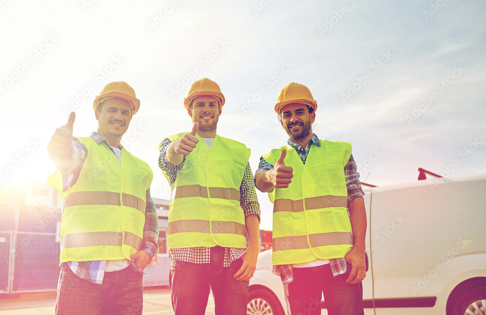 happy male builders in high visible vests outdoors